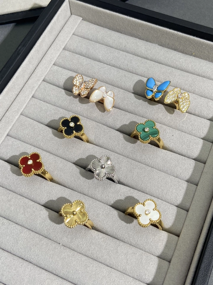 VCA inspired butterfly and clover rings in gold and silver with colorful enamel, displayed in a jewelry box